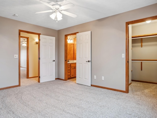 unfurnished bedroom with light carpet, ensuite bath, ceiling fan, a spacious closet, and a closet