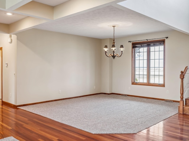 spare room with hardwood / wood-style flooring and a notable chandelier