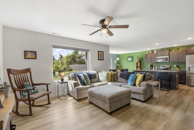 living room featuring ceiling fan, sink, and light hardwood / wood-style floors