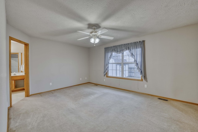 carpeted empty room with ceiling fan and a textured ceiling