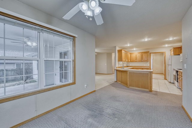 kitchen featuring ceiling fan, kitchen peninsula, light carpet, and light brown cabinetry