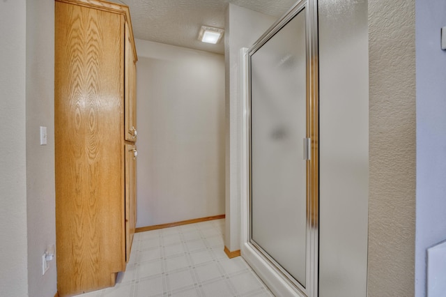 bathroom with a shower with shower door and a textured ceiling