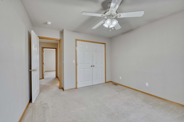 unfurnished bedroom featuring ceiling fan, a closet, and light carpet