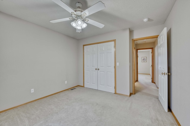 unfurnished bedroom featuring light carpet, a closet, and ceiling fan