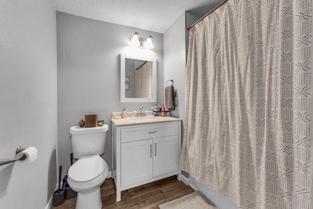 bathroom featuring hardwood / wood-style floors, a textured ceiling, toilet, vanity, and a shower with shower curtain