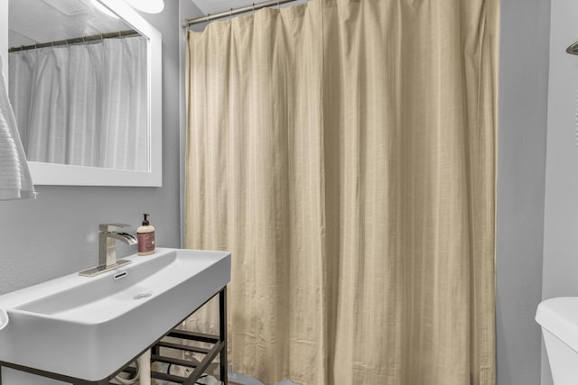 bathroom featuring a shower with shower curtain, toilet, and sink