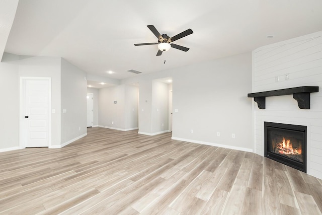 unfurnished living room with ceiling fan, a fireplace, and light hardwood / wood-style flooring