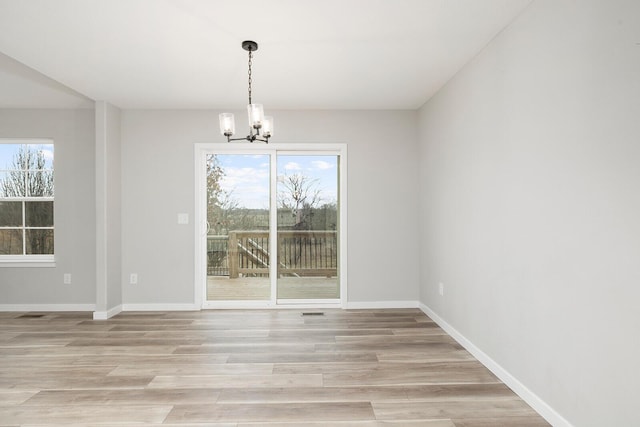 unfurnished dining area with light hardwood / wood-style floors and a notable chandelier