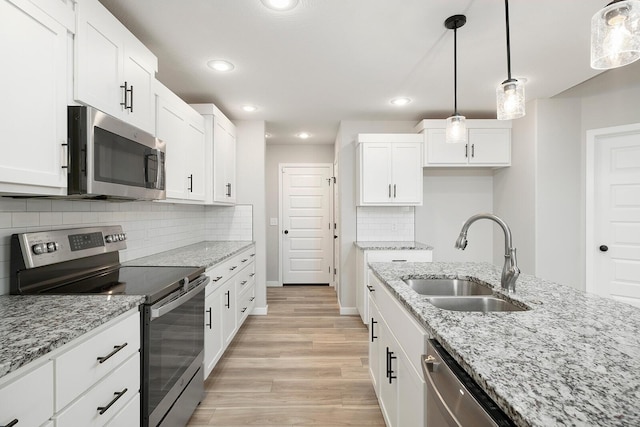 kitchen with white cabinets, sink, hanging light fixtures, light stone countertops, and stainless steel appliances