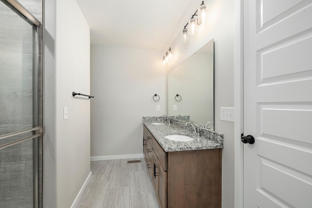 bathroom featuring hardwood / wood-style flooring, vanity, and an enclosed shower