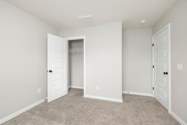 unfurnished bedroom with light colored carpet and a closet