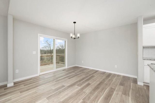 unfurnished dining area featuring a chandelier and light wood-type flooring