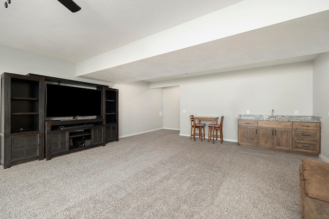 unfurnished living room with a textured ceiling, light colored carpet, and sink