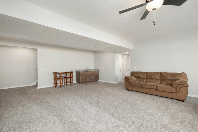 living room featuring carpet flooring, ceiling fan, and a textured ceiling