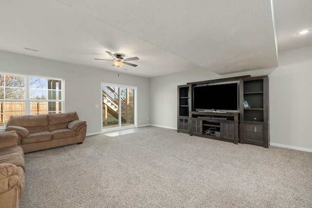 living room featuring ceiling fan, carpet floors, and a textured ceiling