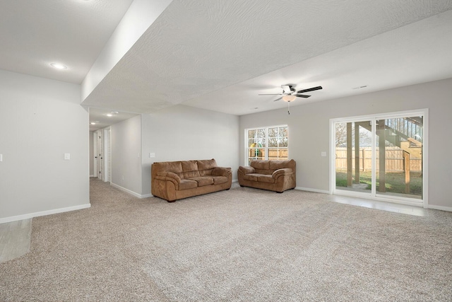 unfurnished living room with light carpet, ceiling fan, and a textured ceiling