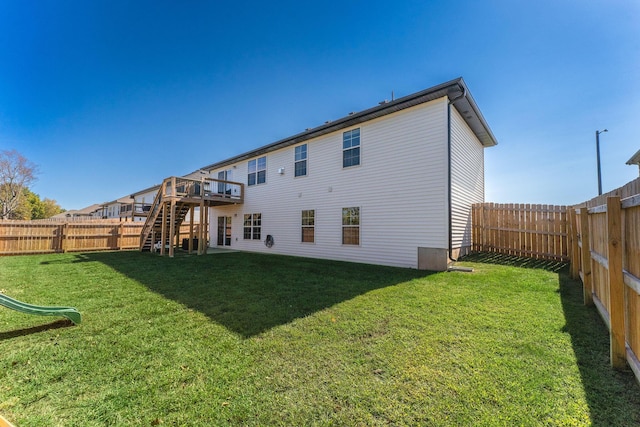 rear view of property featuring a wooden deck and a yard