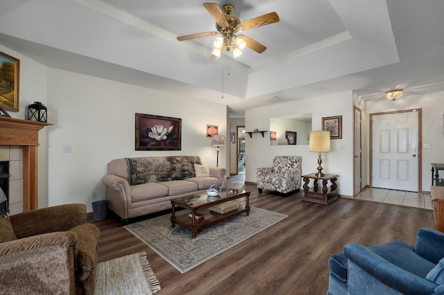 living room with a tray ceiling, a fireplace, ceiling fan, and hardwood / wood-style floors