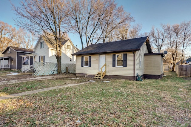 bungalow with entry steps, fence, and a front yard