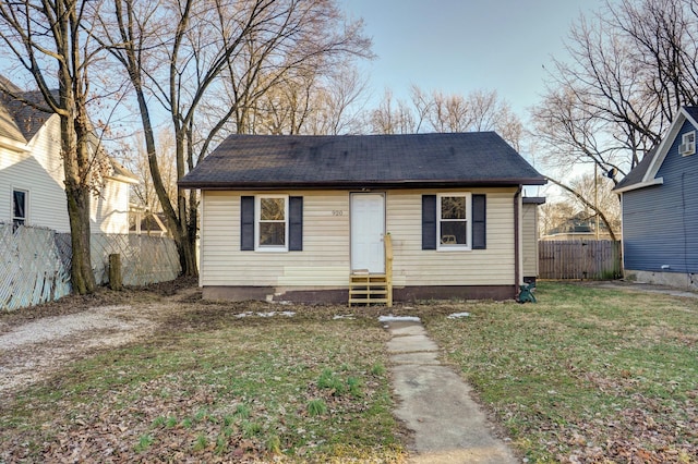 bungalow-style home featuring entry steps, fence, and a front lawn