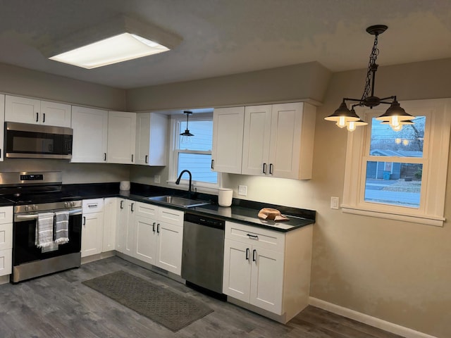 kitchen featuring a notable chandelier, white cabinets, sink, appliances with stainless steel finishes, and decorative light fixtures