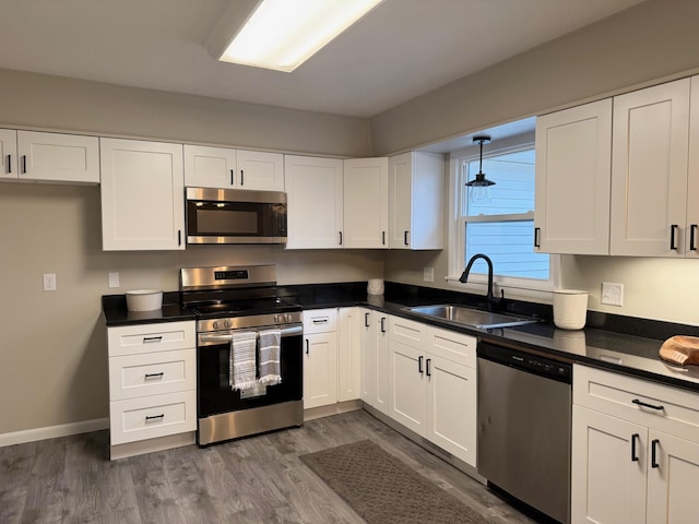 kitchen with white cabinets, sink, appliances with stainless steel finishes, and dark wood-type flooring