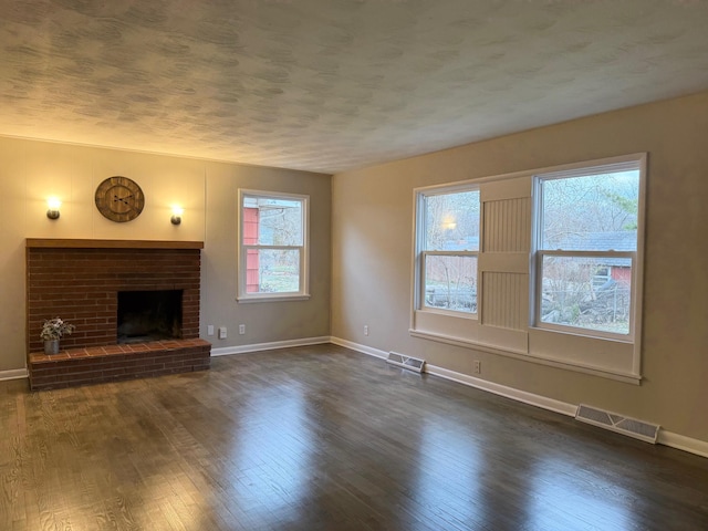 unfurnished living room featuring a wealth of natural light, a fireplace, and dark wood-type flooring