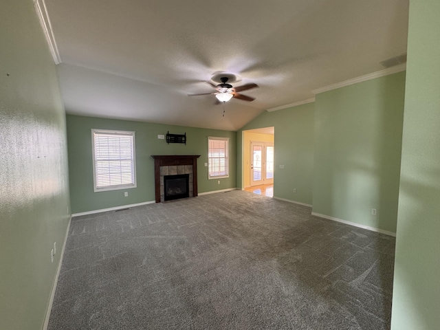 unfurnished living room with dark carpet, lofted ceiling, a tile fireplace, crown molding, and ceiling fan