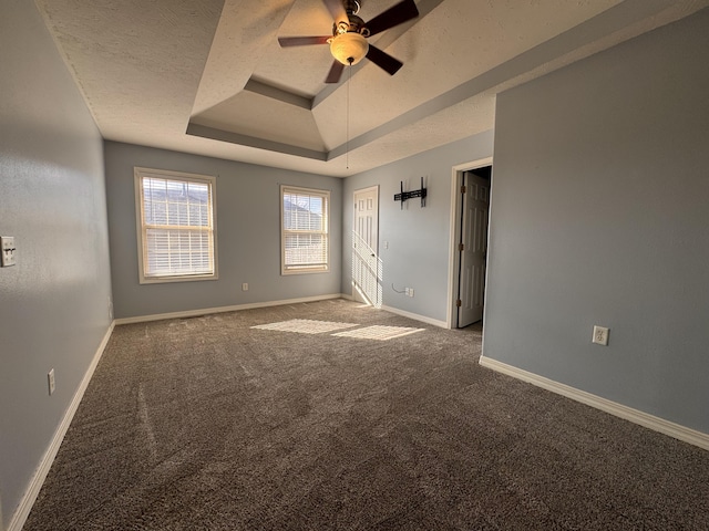 carpeted empty room with ceiling fan, a textured ceiling, and a tray ceiling