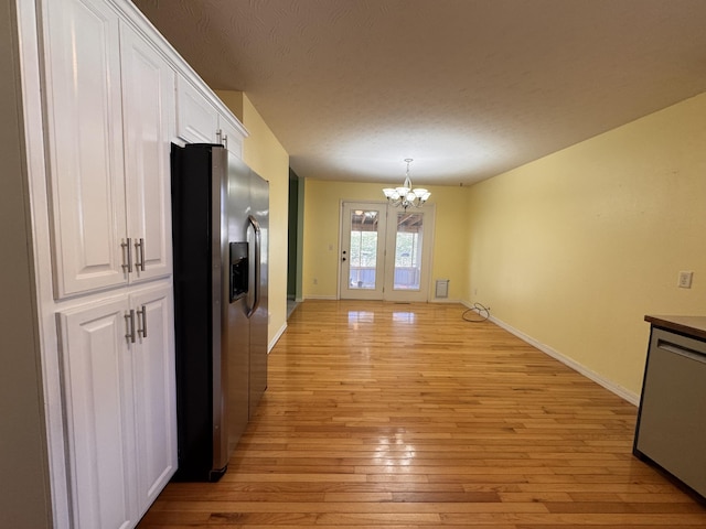 kitchen with stainless steel appliances, a notable chandelier, white cabinets, light hardwood / wood-style floors, and hanging light fixtures