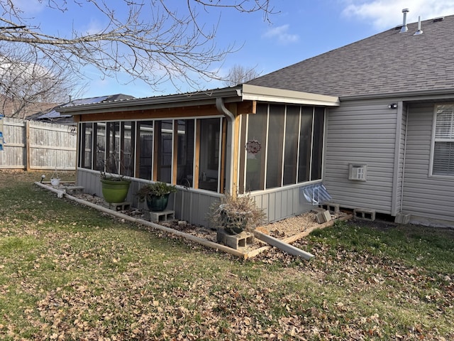 rear view of house featuring a lawn and a sunroom