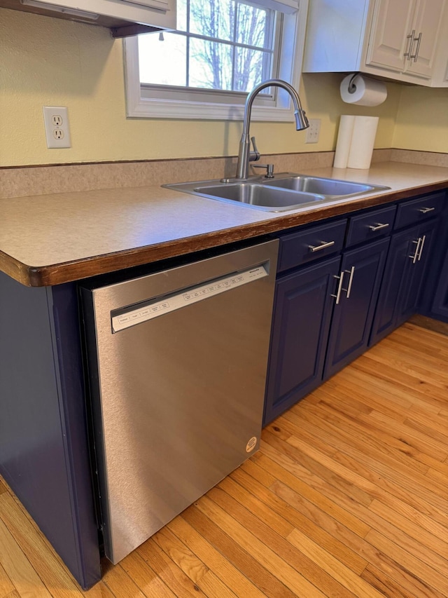 kitchen featuring light wood-type flooring, stainless steel dishwasher, sink, blue cabinetry, and white cabinets