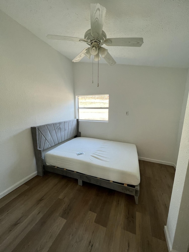 bedroom featuring ceiling fan, dark wood-type flooring, and a textured ceiling