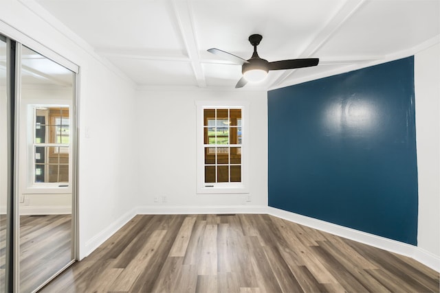 empty room with beam ceiling, hardwood / wood-style floors, a healthy amount of sunlight, and coffered ceiling