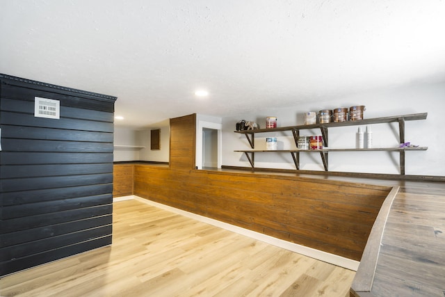 bar with light hardwood / wood-style floors and wooden walls