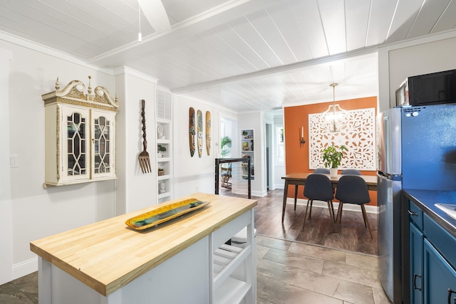 kitchen with pendant lighting, wood counters, an inviting chandelier, stainless steel fridge, and ornamental molding