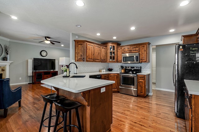 kitchen featuring sink, stainless steel appliances, tasteful backsplash, kitchen peninsula, and a kitchen bar