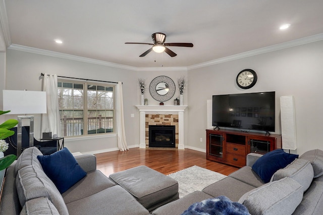 living room with a tile fireplace, wood-type flooring, ceiling fan, and ornamental molding