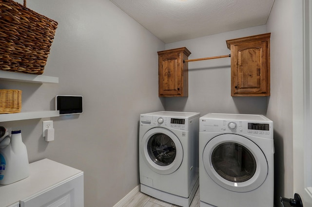 clothes washing area with cabinets, a textured ceiling, light hardwood / wood-style floors, and washer and dryer