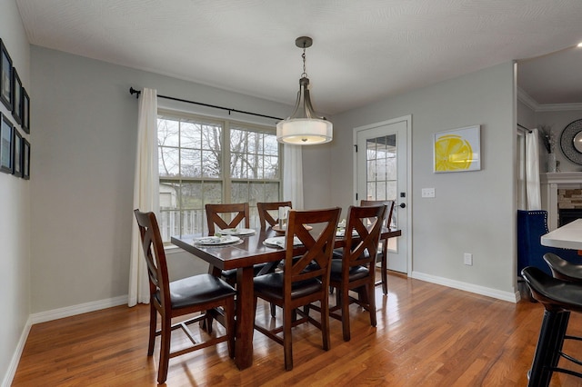 dining area featuring a fireplace, ornamental molding, and hardwood / wood-style flooring