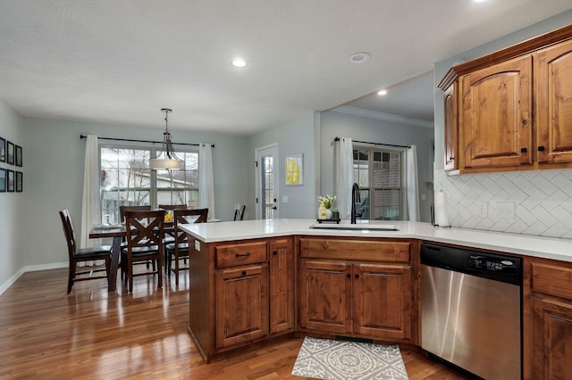 kitchen with backsplash, sink, hanging light fixtures, stainless steel dishwasher, and kitchen peninsula