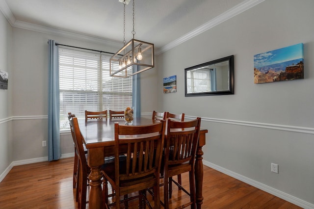 dining space with hardwood / wood-style flooring, a notable chandelier, and crown molding