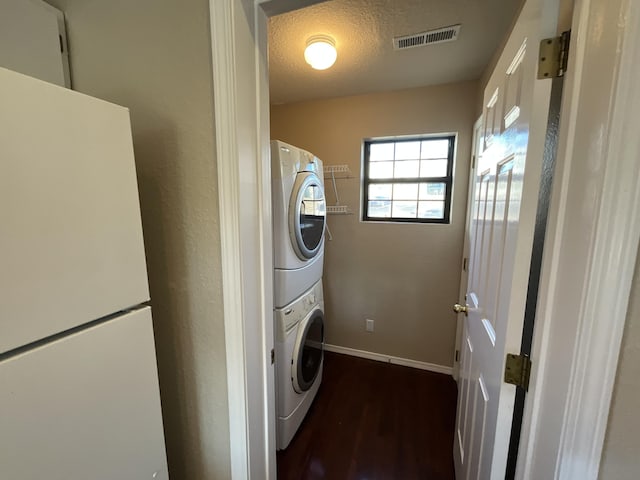 laundry room with dark hardwood / wood-style floors, a textured ceiling, and stacked washer and clothes dryer