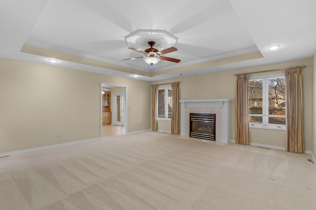 unfurnished living room with a raised ceiling, ceiling fan, and light colored carpet