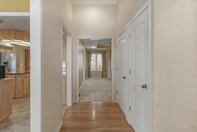 corridor with light wood-type flooring and crown molding