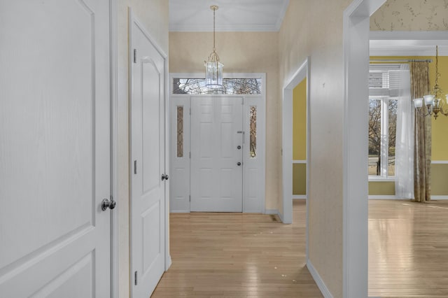 entryway with a chandelier, light wood-type flooring, and crown molding