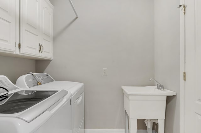 clothes washing area featuring washing machine and clothes dryer, sink, and cabinets