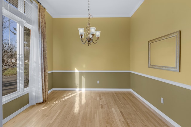 spare room featuring wood-type flooring, ornamental molding, and a chandelier