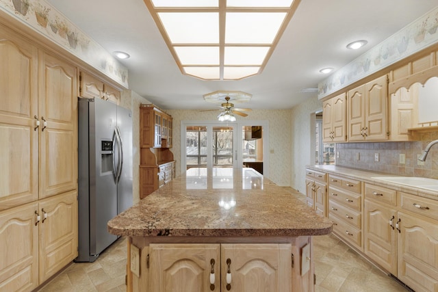 kitchen with a kitchen island, sink, stainless steel refrigerator with ice dispenser, and tasteful backsplash