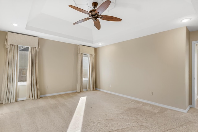 carpeted spare room with ceiling fan and a tray ceiling